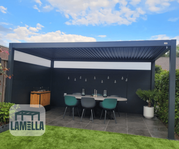 Eine moderne Außenterrasse präsentiert eine elegante Pergola mit Lamellendach Elektrisch, dazu einen Esstisch und Stühle auf gefliestem Boden. Links stehen ein Schrank und ein Grill, während eine Topfpflanze die rechte Seite schmückt. Die Szene spielt vor einem Hintergrund aus blauem Himmel mit Wolken. In der unteren linken Ecke befindet sich das LAMELLA-Logo.