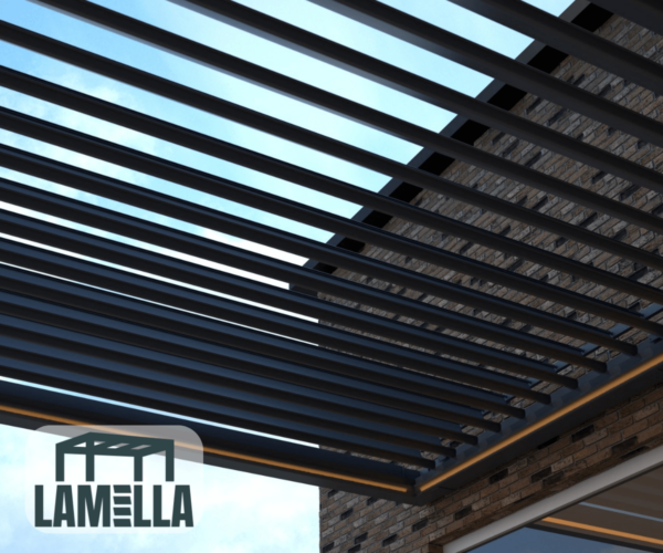 Ein Blick nach oben auf eine elegante, moderne Pergola, die an ein raffiniertes Lamellendach nach Maß erinnert, mit gleichmäßig angeordneten dunklen Metalllamellen vor einem klaren blauen Himmel. Ein Teil eines Backsteingebäudes ist sichtbar, während in der unteren linken Ecke das Lamella-Logo zu sehen ist.