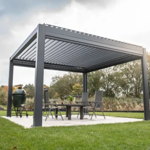 Eine moderne Pergola mit Lamellendach steht auf einer Terrasse, die von einem gepflegten Rasen umgeben ist. Darunter befindet sich ein Essbereich mit Stühlen und einem Grill. Im Hintergrund sind Bäume und ein bewölkter Himmel zu sehen.