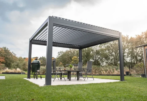 Eine moderne Pergola mit Lamellendach steht auf einer Terrasse, die von einem gepflegten Rasen umgeben ist. Darunter befindet sich ein Essbereich mit Stühlen und einem Grill. Im Hintergrund sind Bäume und ein bewölkter Himmel zu sehen.