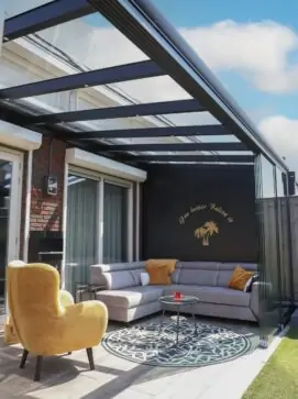 Eine Pergola mit Glasdach, mit Wohnecke unten drunter.