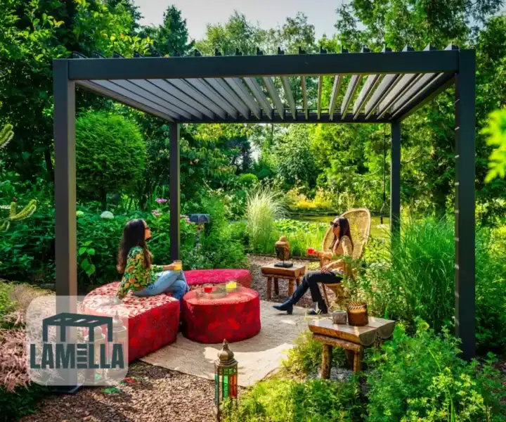 Zwei Menschen sitzen unter einer modernen Pergola in einem üppigen Garten, umgeben von roten, gemusterten runden Sitzgelegenheiten und Holztischen. Eine Laterne steht auf dem Boden. Sonnenlicht fällt durch die Bäume und wirft Schatten. In der linken unteren Ecke ist ein Lamella-Logo zu sehen.