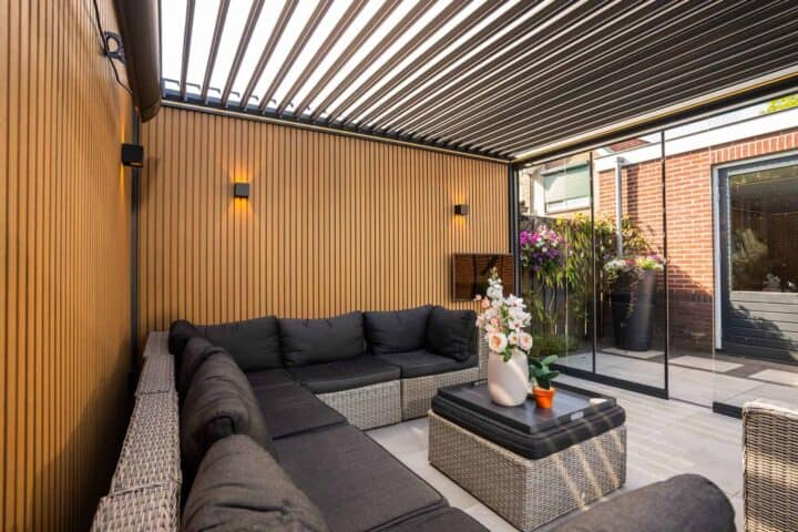 Holzpaneele und Beleuchtung unter einer Lamellenüberdachung mit Loungeset auf der Terrasse.