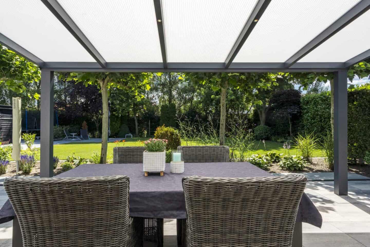 Lamella Polycarbonat Überdachung mit Blick auf einen grünen Garten und eine Esstisch-Garnitur.