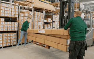Zwei Mitarbeiter die Pakete im Lager stapeln.