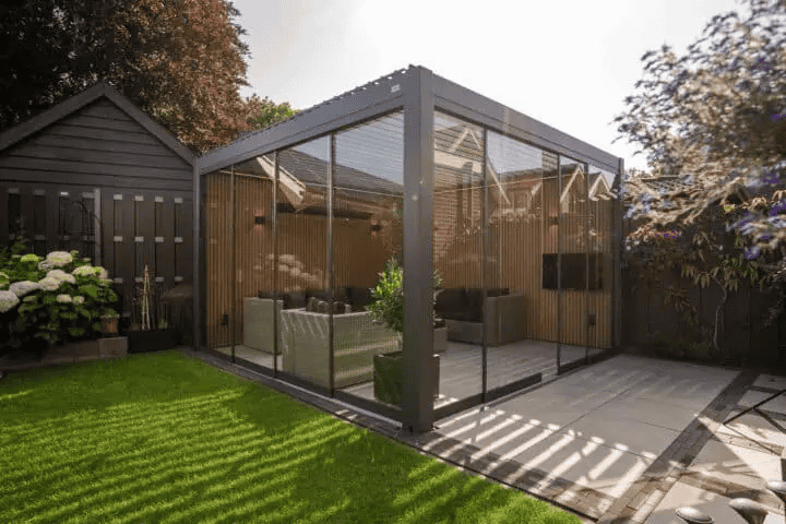Glas Terrassenüberdachung im kleinen Garten für Schutz und Gemütlichkeit.